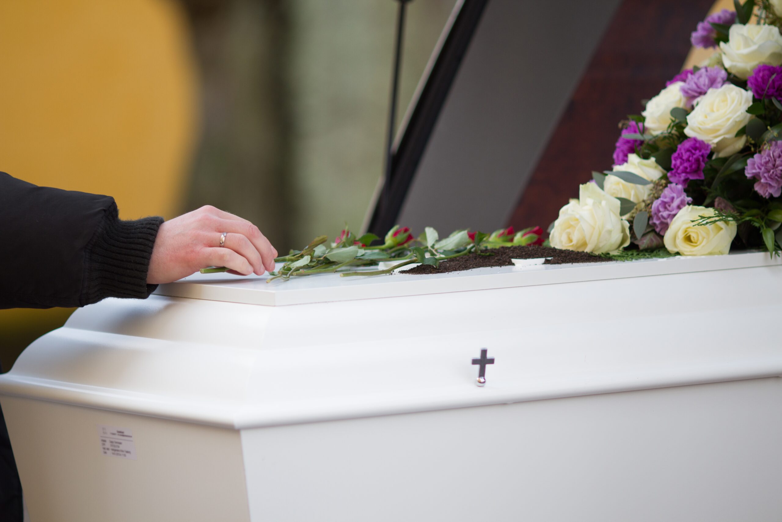 Closeup shot of a person hand on a casket with a blurred background