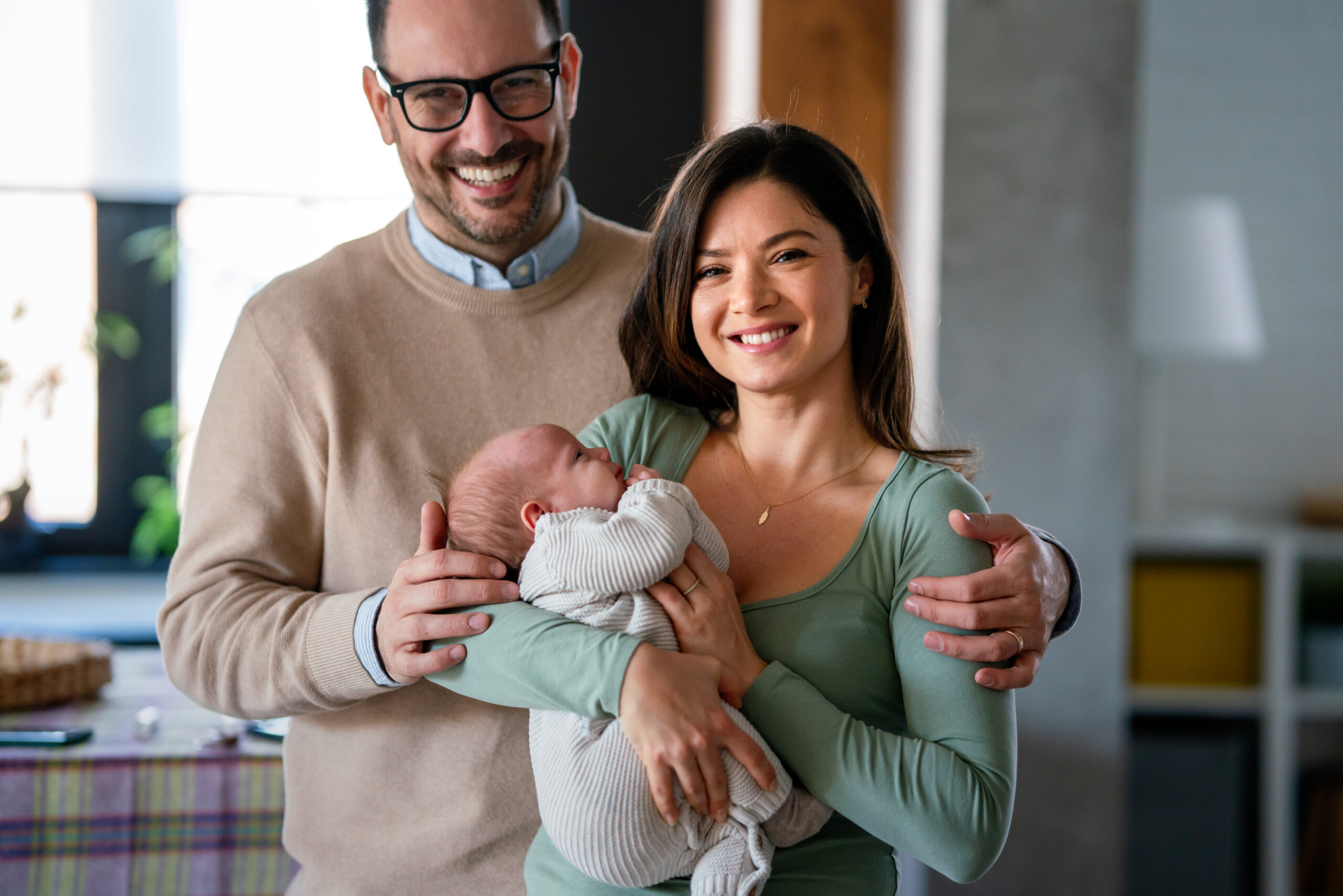 Family, adoption, baby, parenthood and people concept. Happy mother father with newborn baby at home